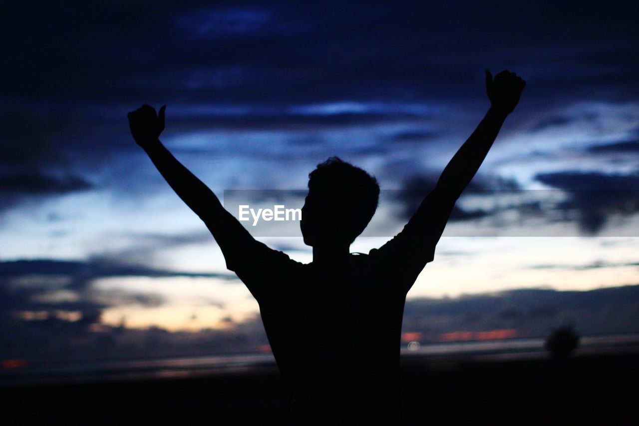 REAR VIEW OF SILHOUETTE PERSON STANDING IN SEA AGAINST SKY