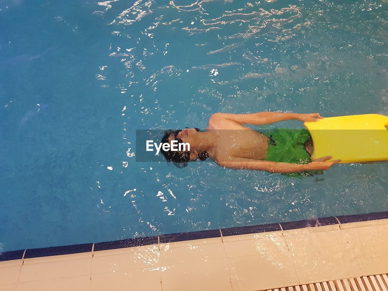 HIGH ANGLE VIEW OF MAN SWIMMING IN POOL AT NIGHT