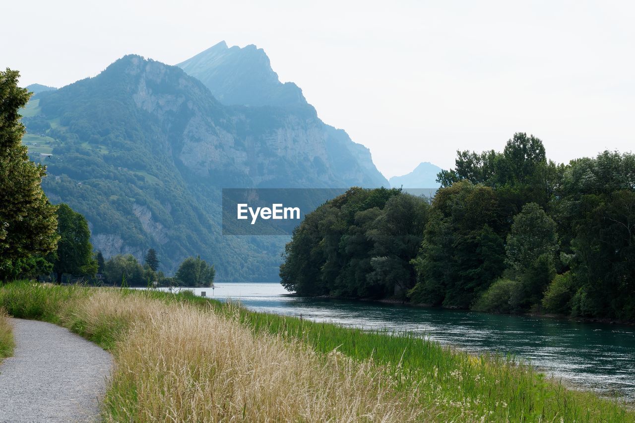 Scenic view of river by mountains against sky