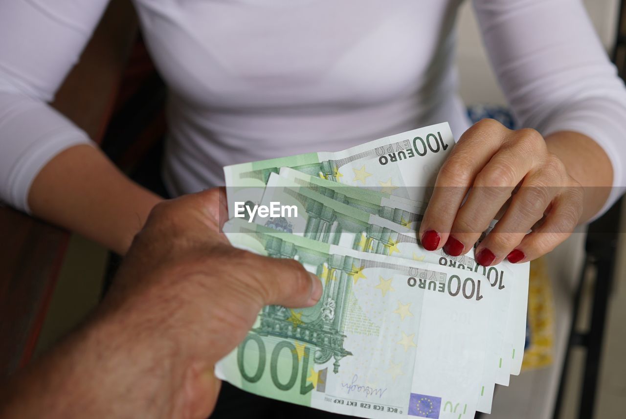 Midsection of businesswoman receiving money from man