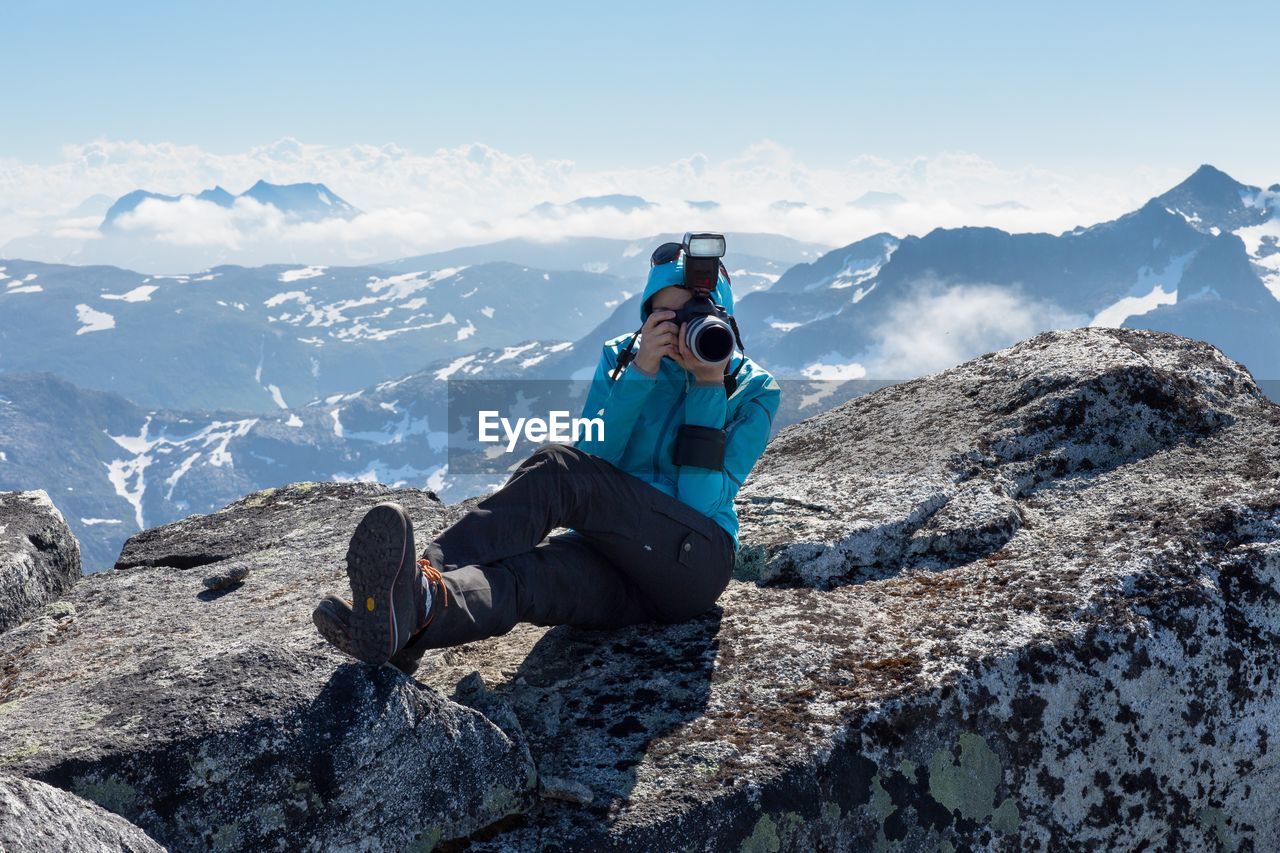 Man photographing while sitting on mountain