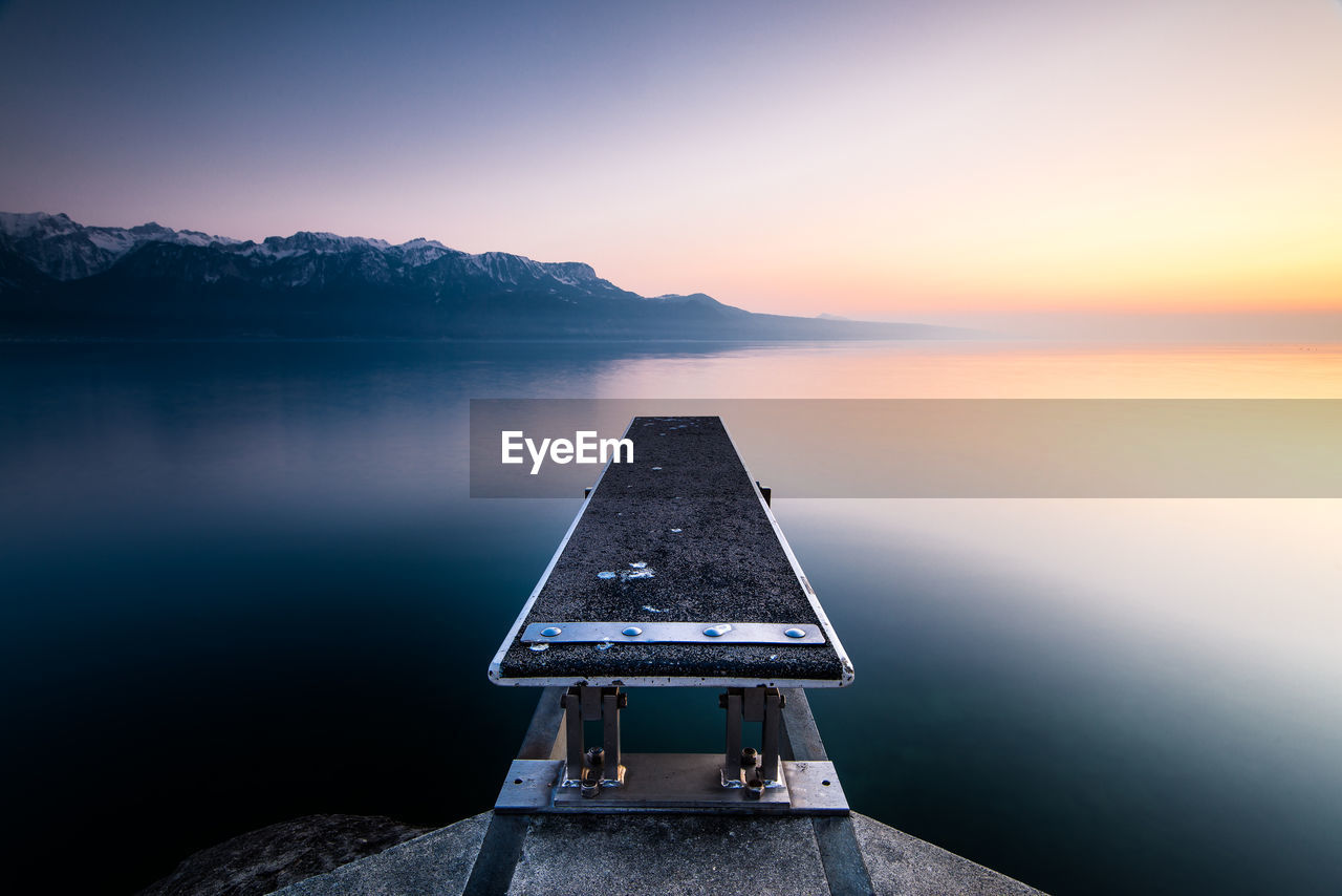 Equipment over calm sea against clear sky during sunset