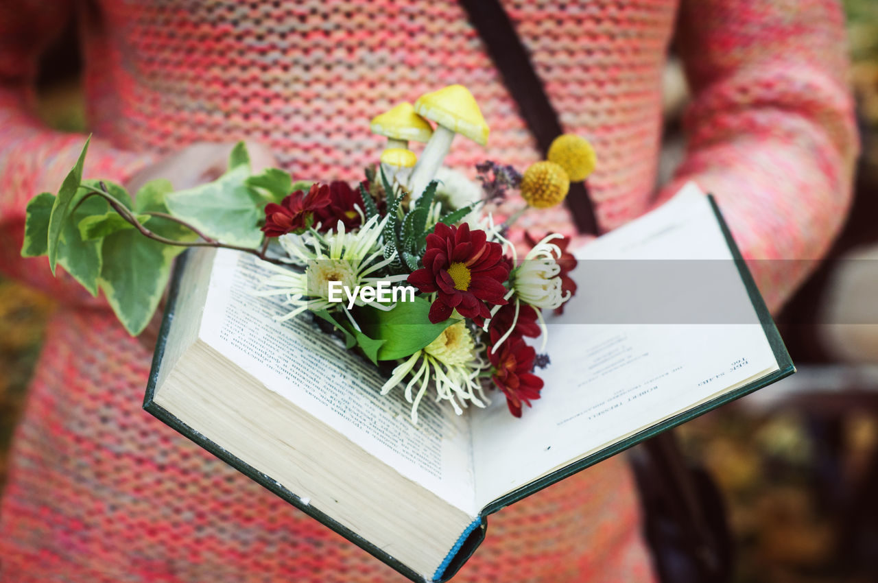 Colored flower arrangement in a vintage book in the hands of a model