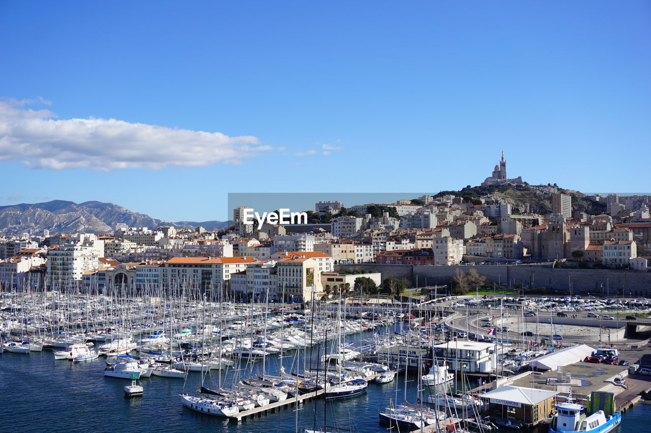 Sailboats in city against blue sky