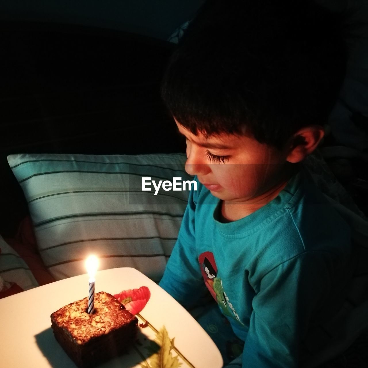 HIGH ANGLE VIEW OF BOY ON TABLE AGAINST ILLUMINATED DARK