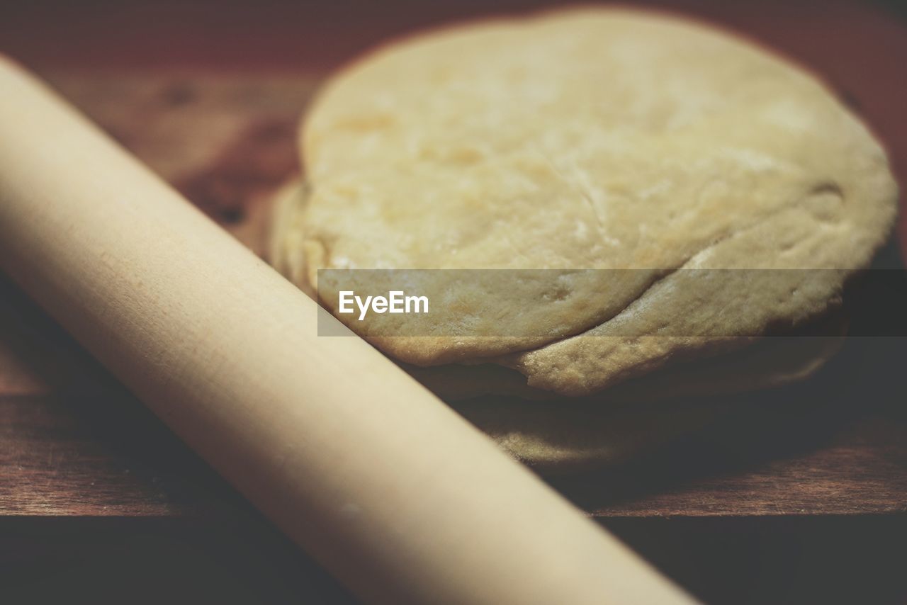 Close-up of dough and rolling pin on wooden table