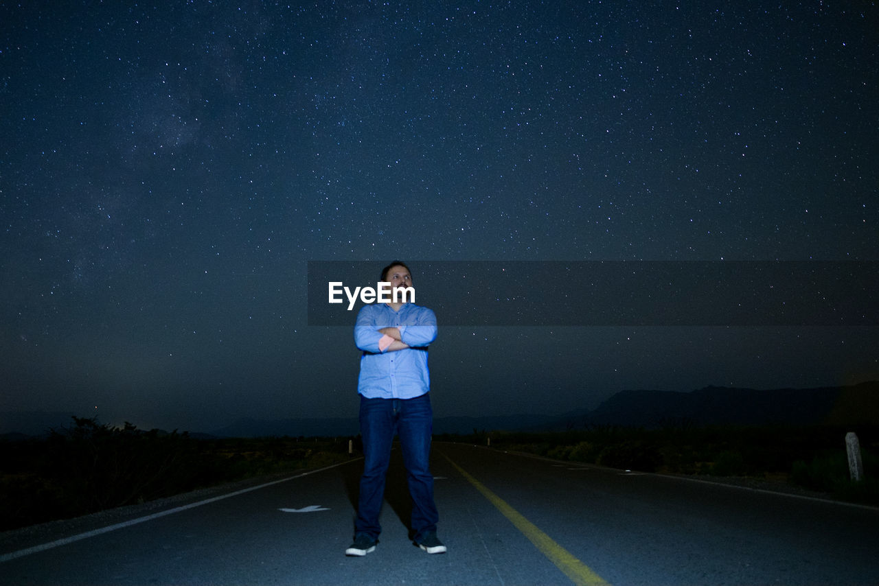 Full length of man standing on road against sky at night