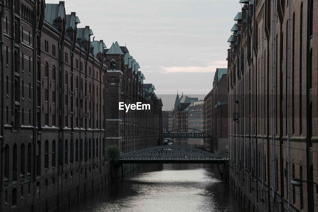 Canal amidst buildings against sky in city