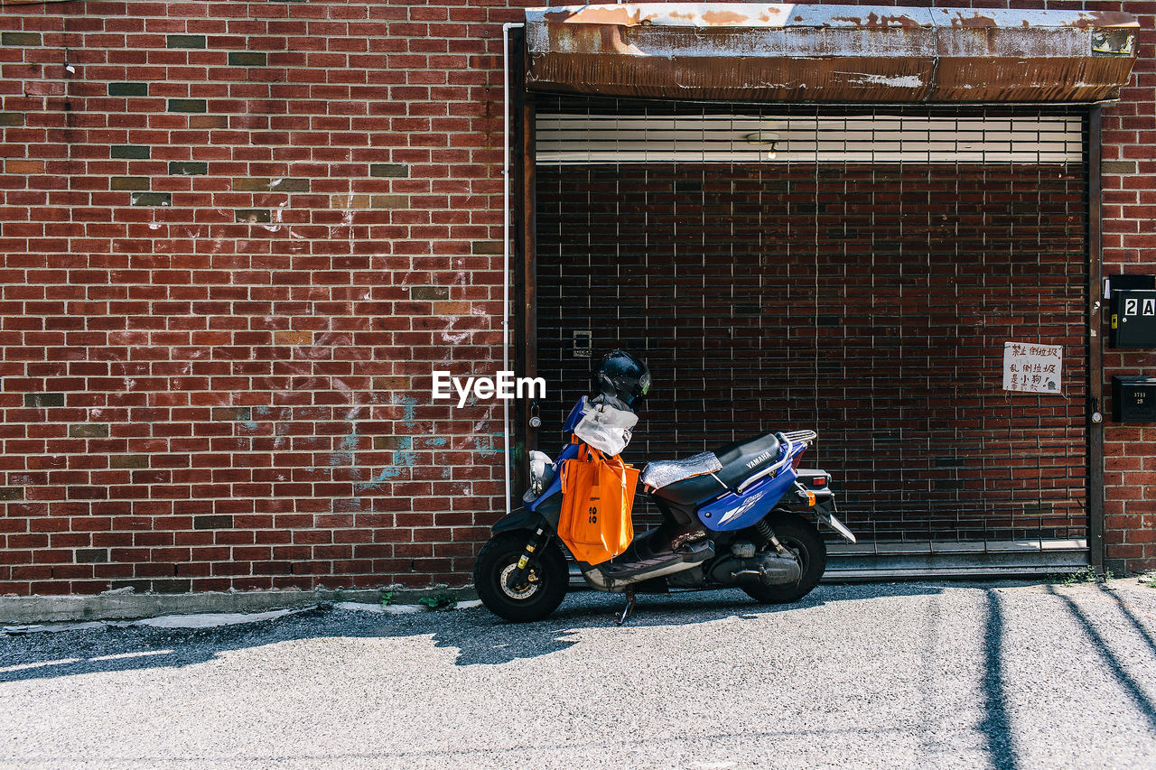 Motor scooter parked on street against building