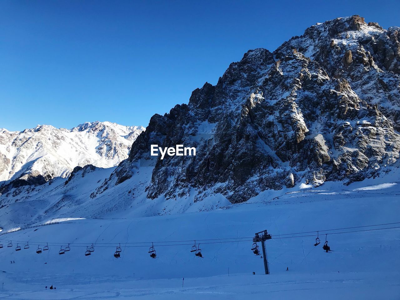 Scenic view of snow covered mountains against clear blue sky