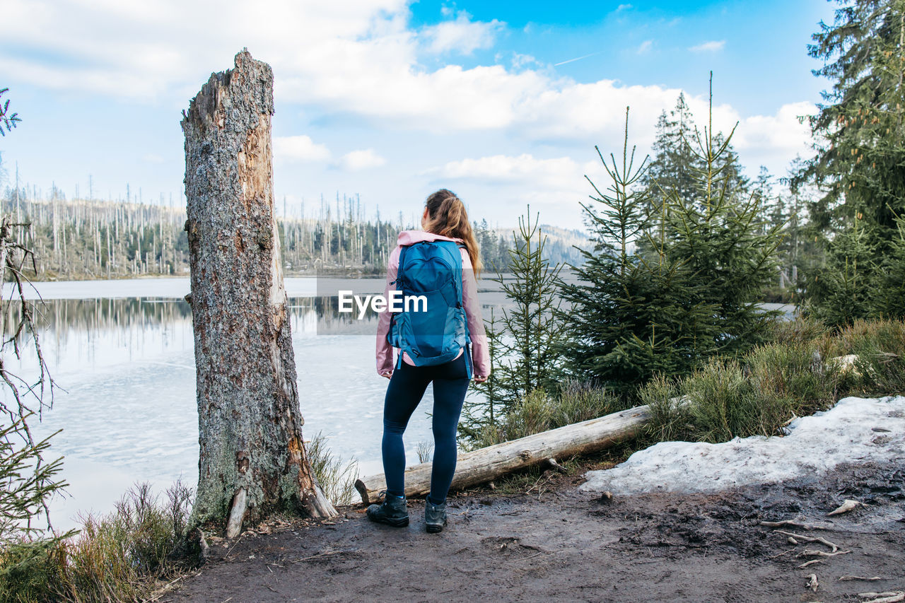 A young woman traveler with a backpack on her back enjoys the views in the spring forest. hiking