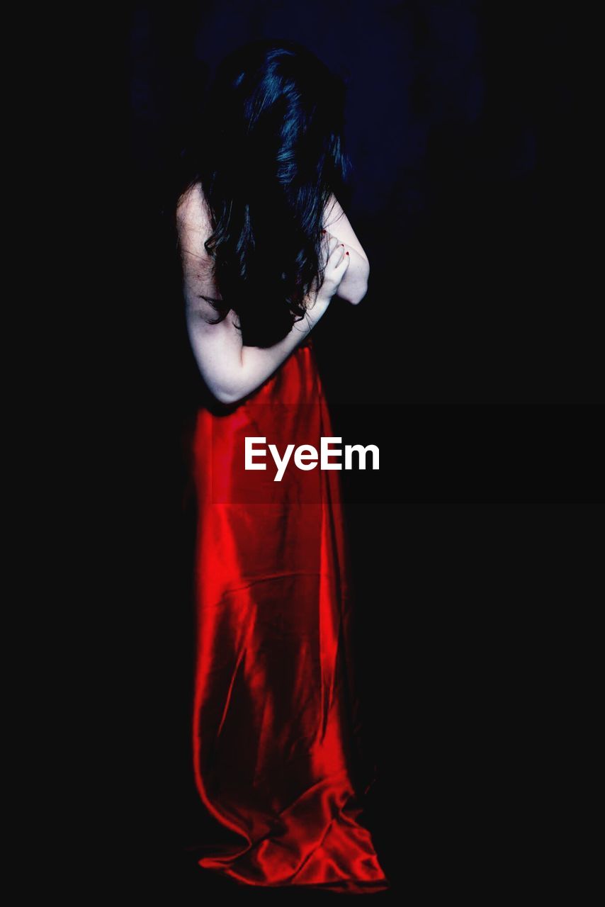 Woman in red gown with long hair against black background