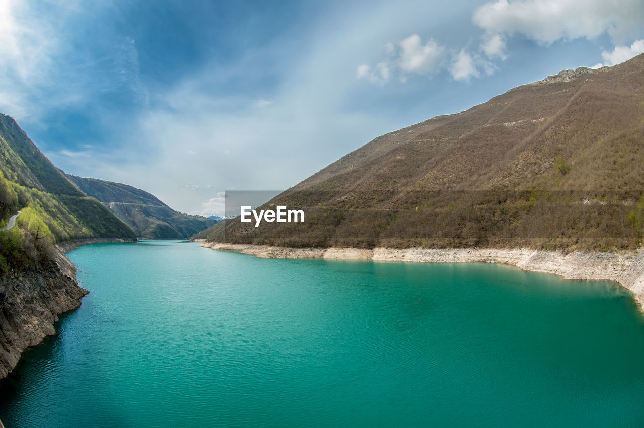 Scenic view of lake by mountains against sky