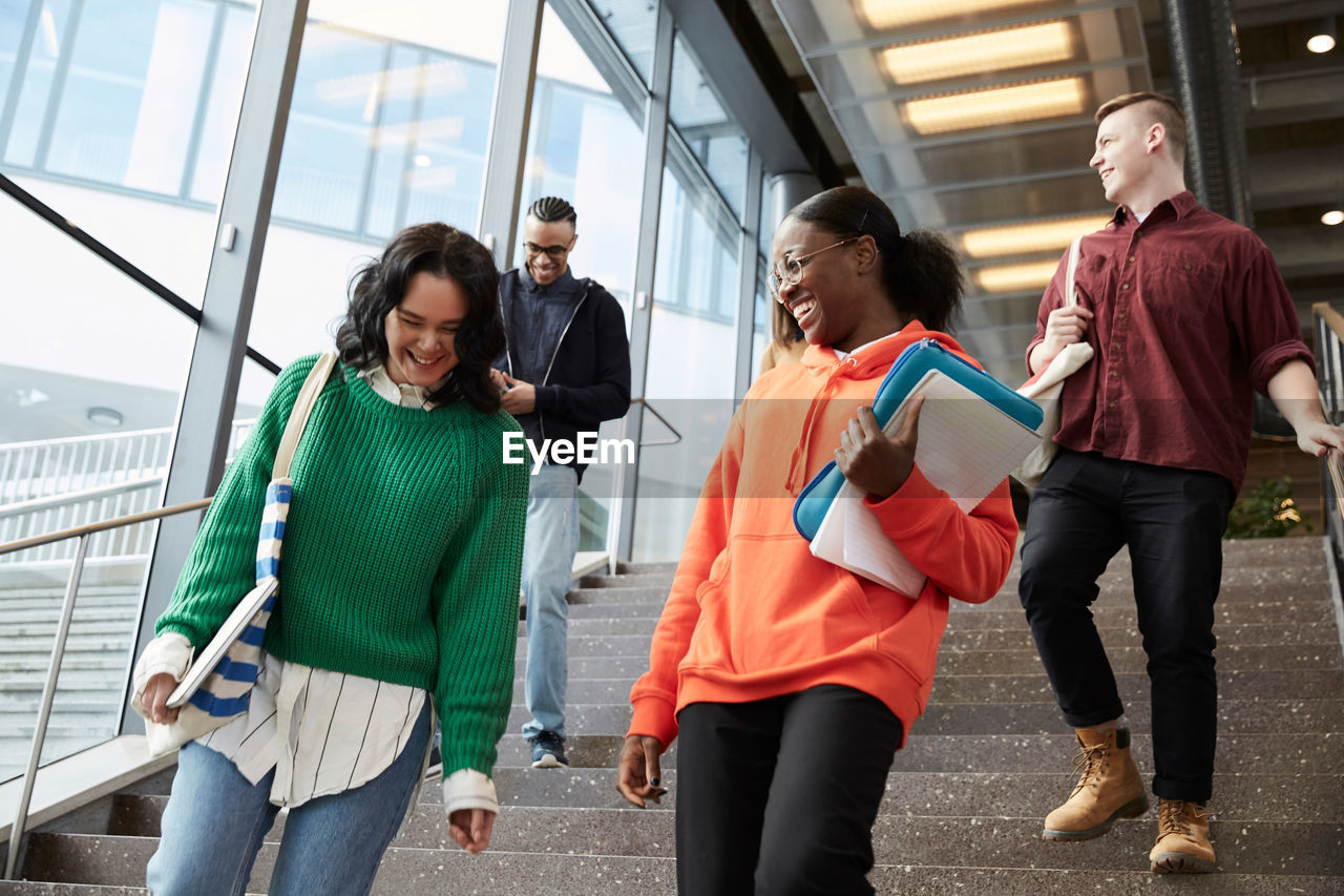 Low angle view of happy university students walking down on steps