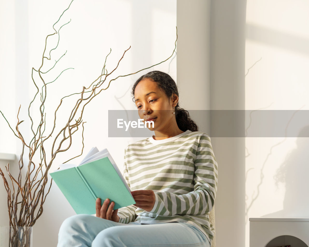 African-american female peacefully reading book in lounge. enjoying moment. slow living lifestyle