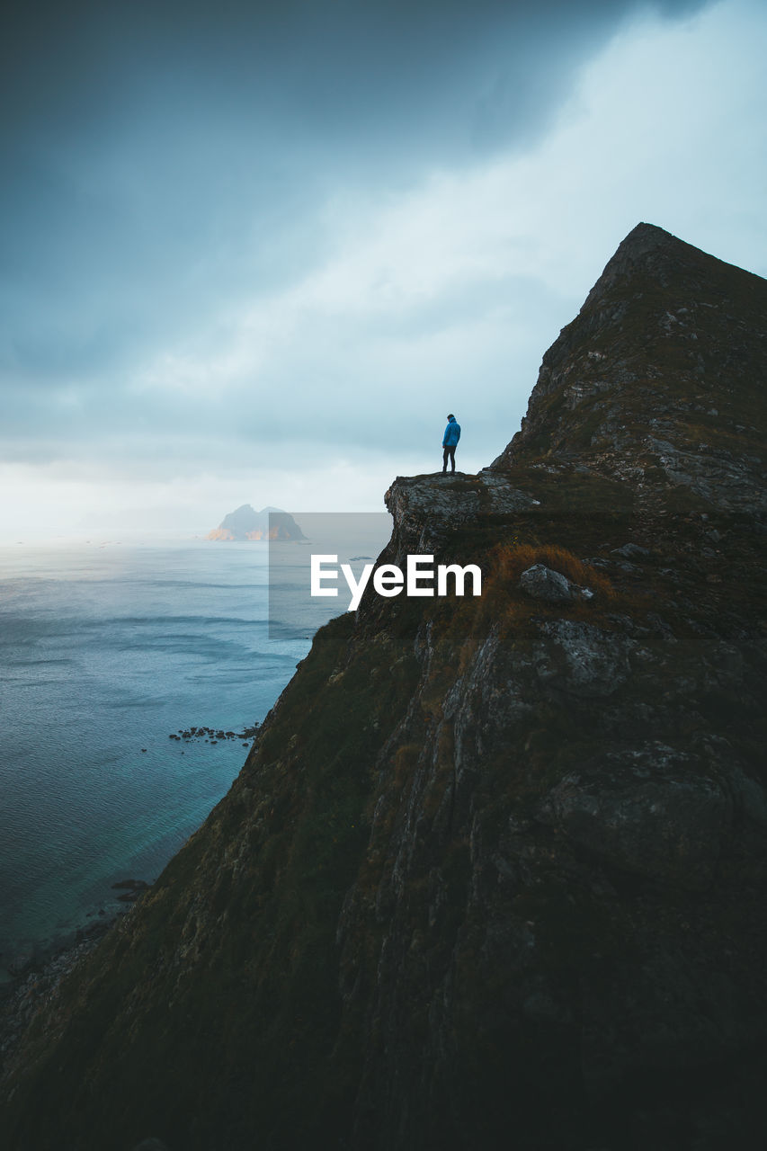 Man standing on mountain by sea against sky