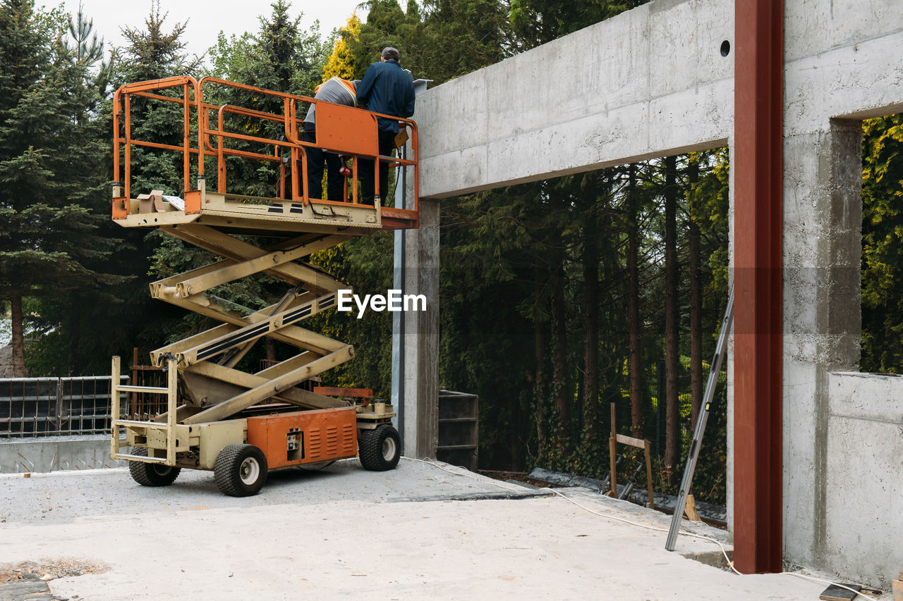 Scissor lift platform with workers on a construction site. building concreate house with mobile