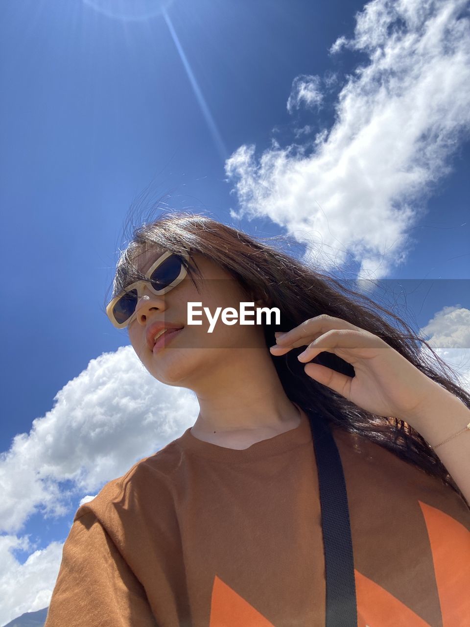 Low angle view of woman wearing sunglasses against sky