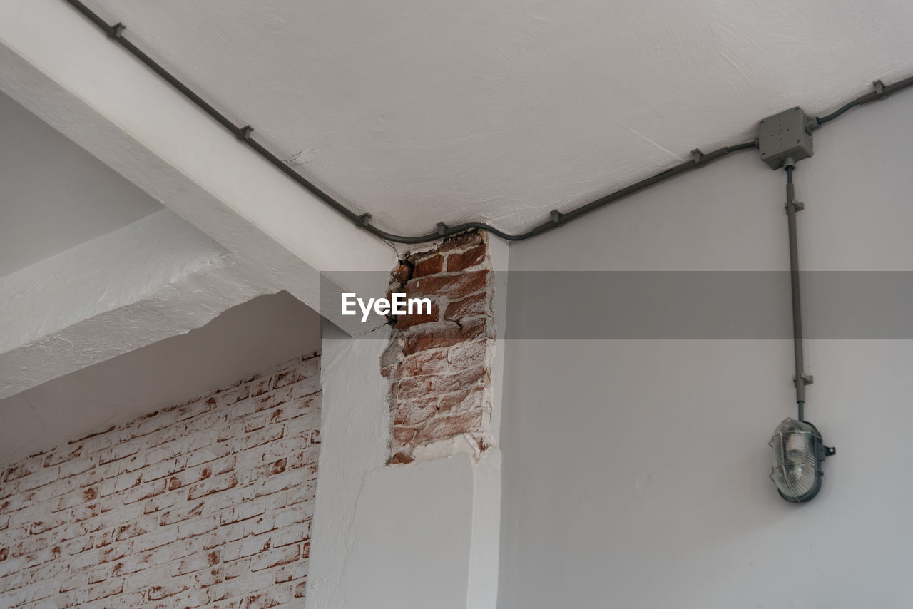 Low angle view of damaged white brick wall