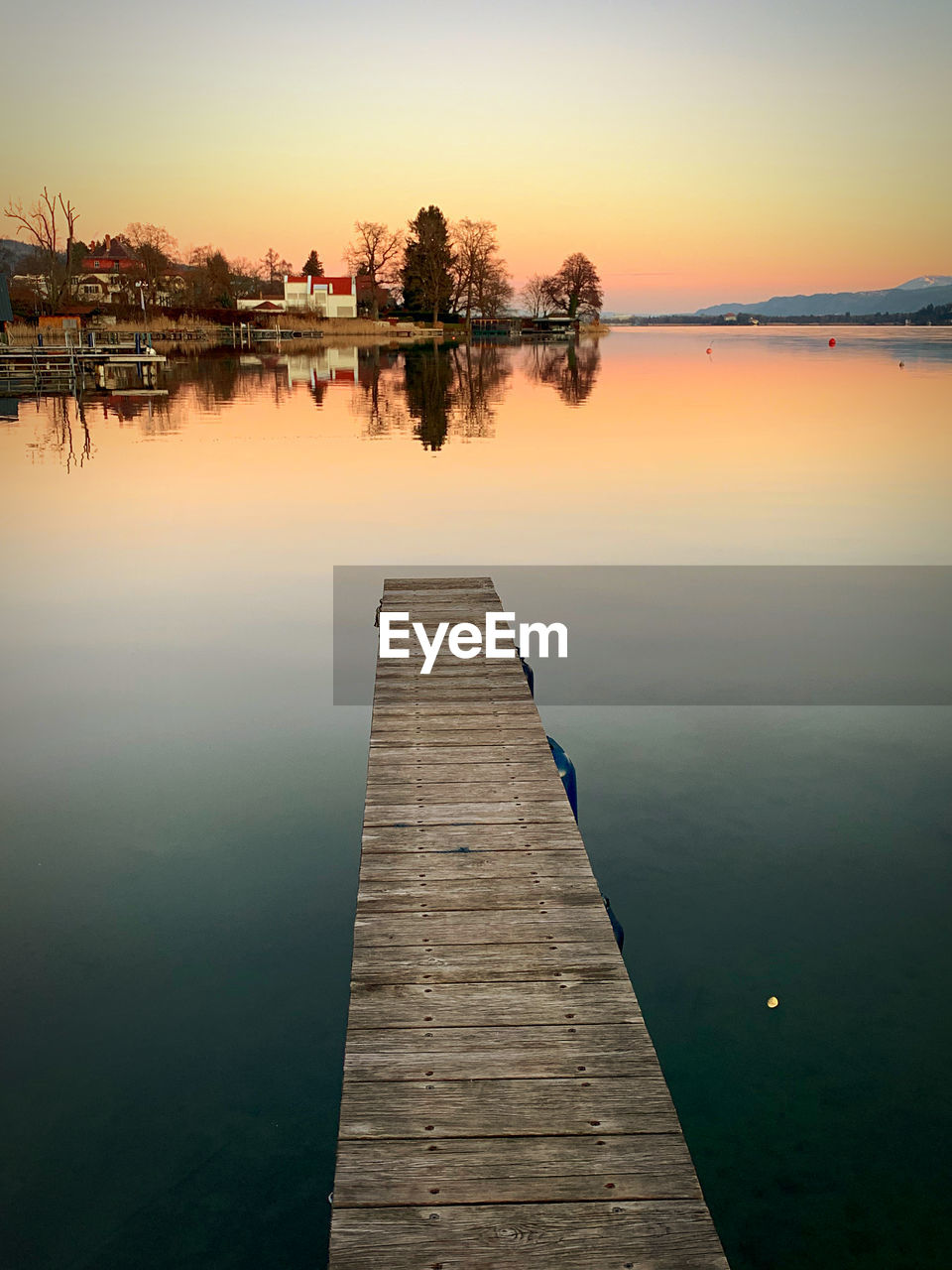 Pier over lake against sky during sunset