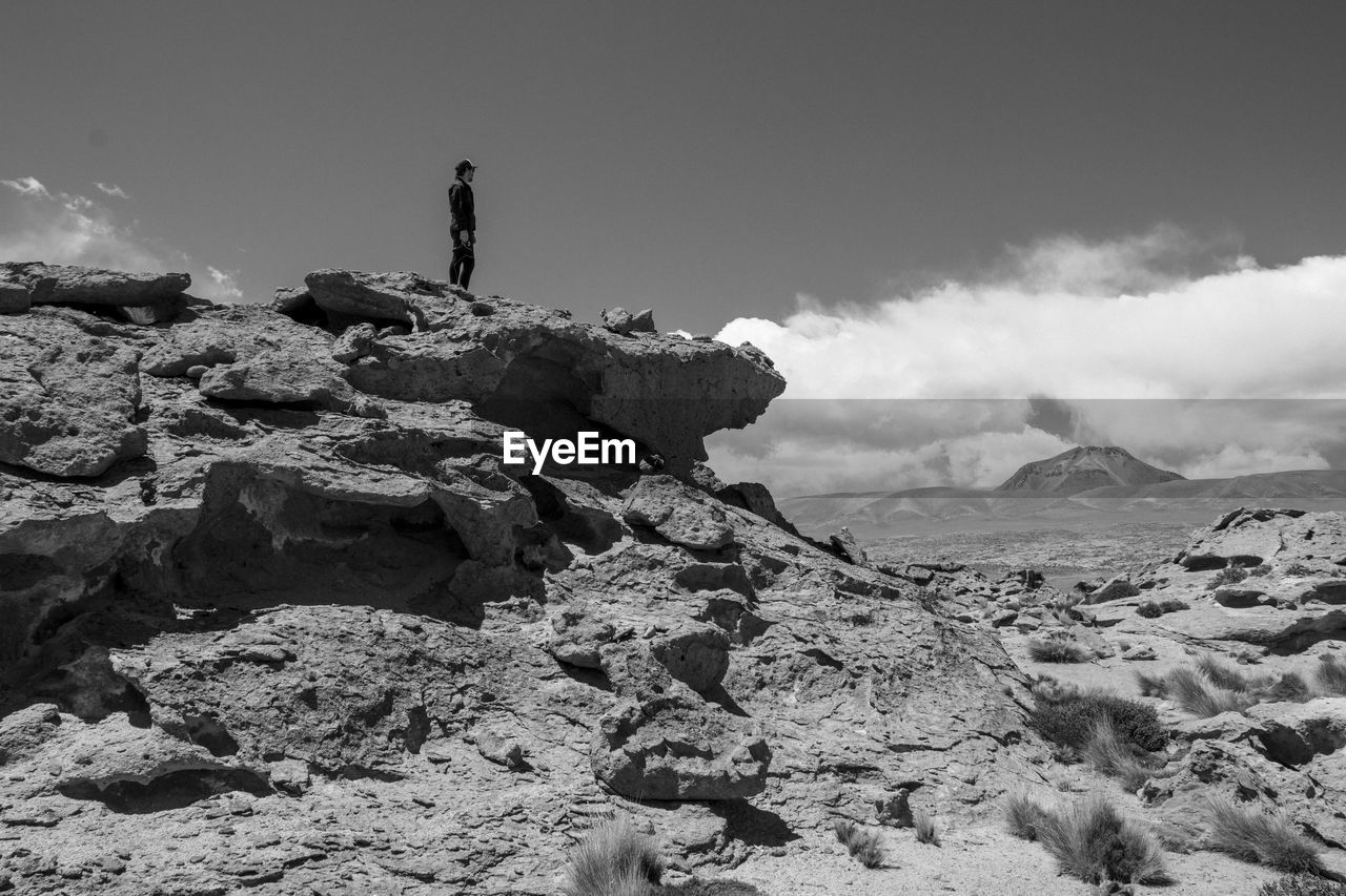 Man standing on rock against sky