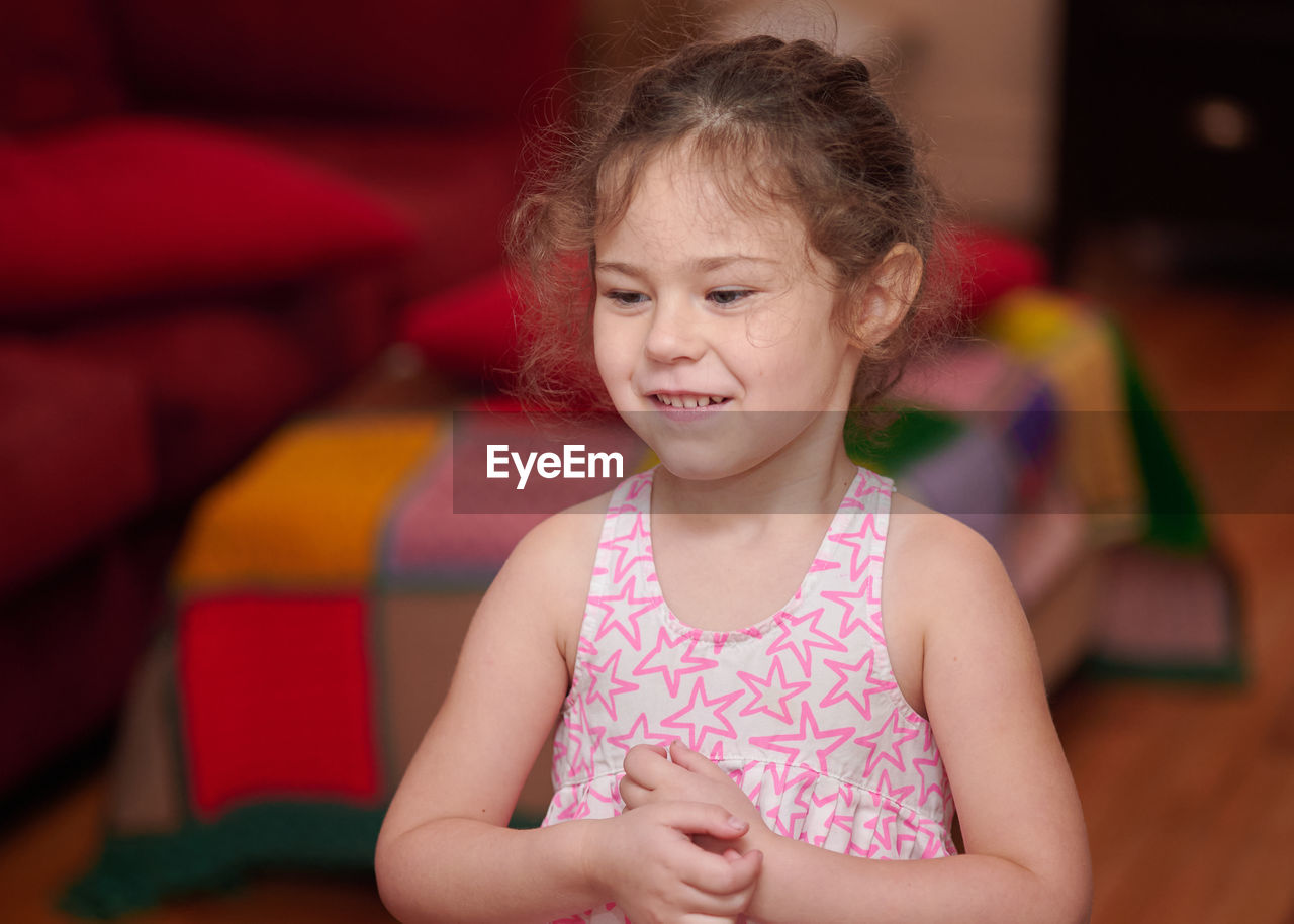 Portrait of a young girl in the livingroom at home making faces and signs of the camera