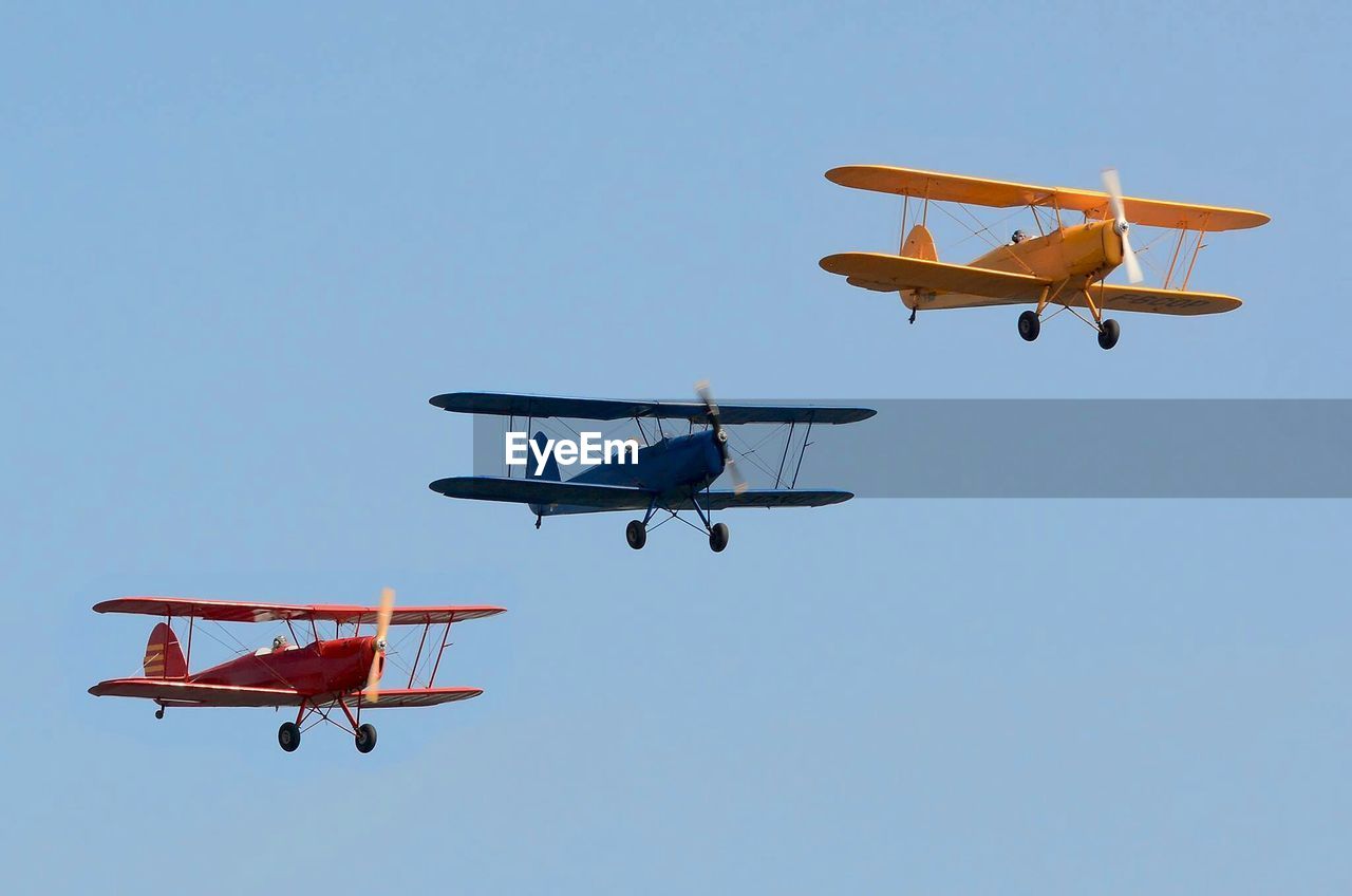 Three biplanes flying in sky