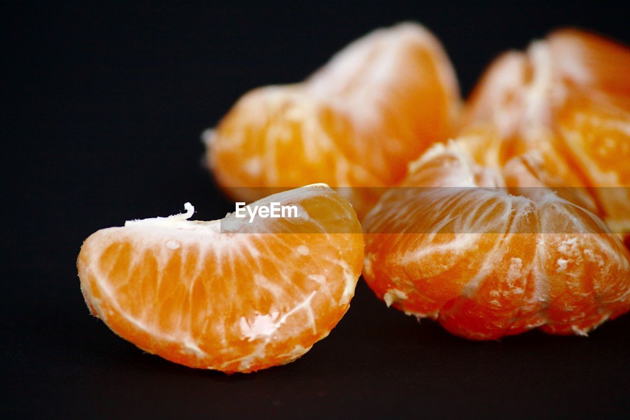 CLOSE-UP OF ORANGE FRUIT AGAINST BLACK BACKGROUND