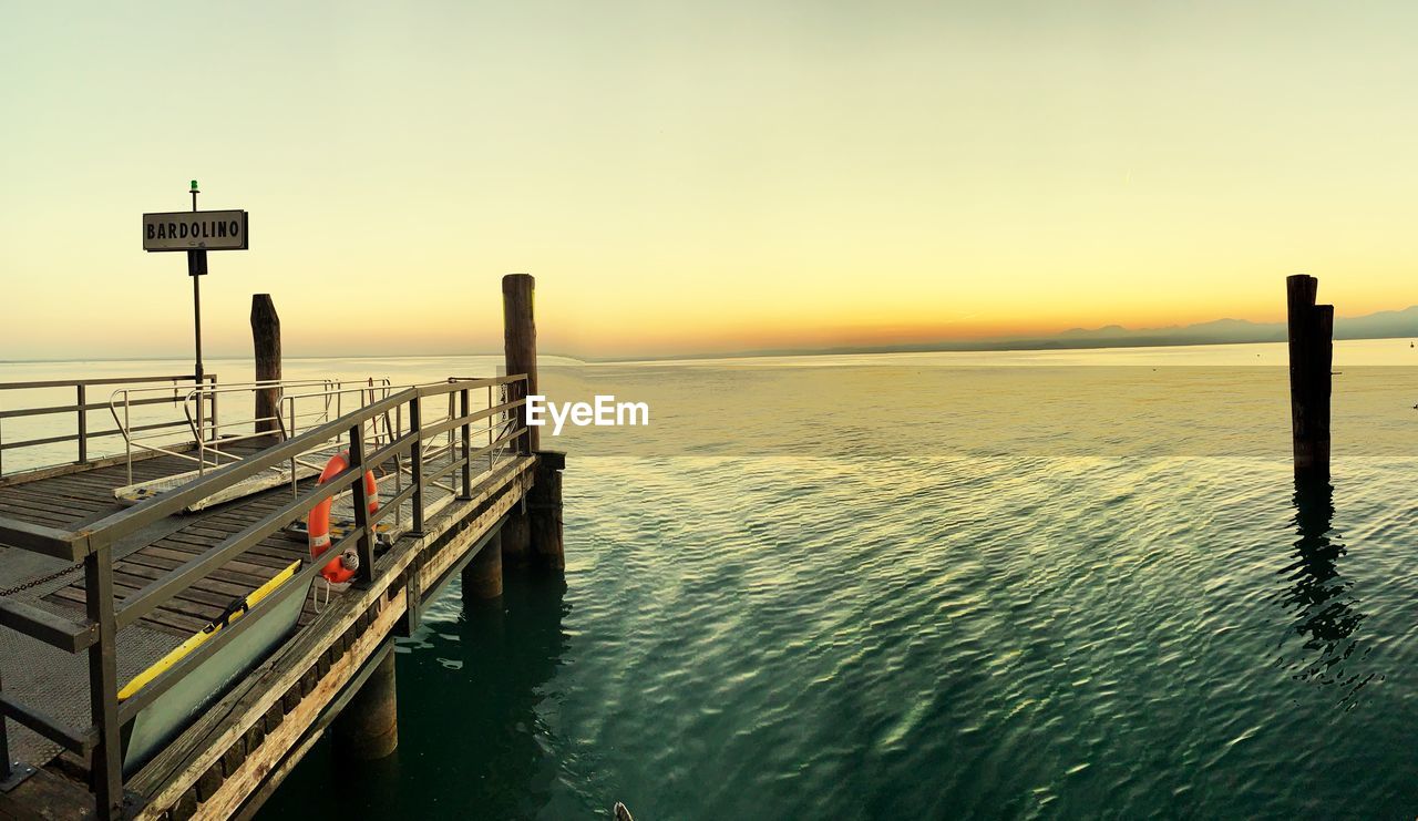 Pier on sea against sky during sunset