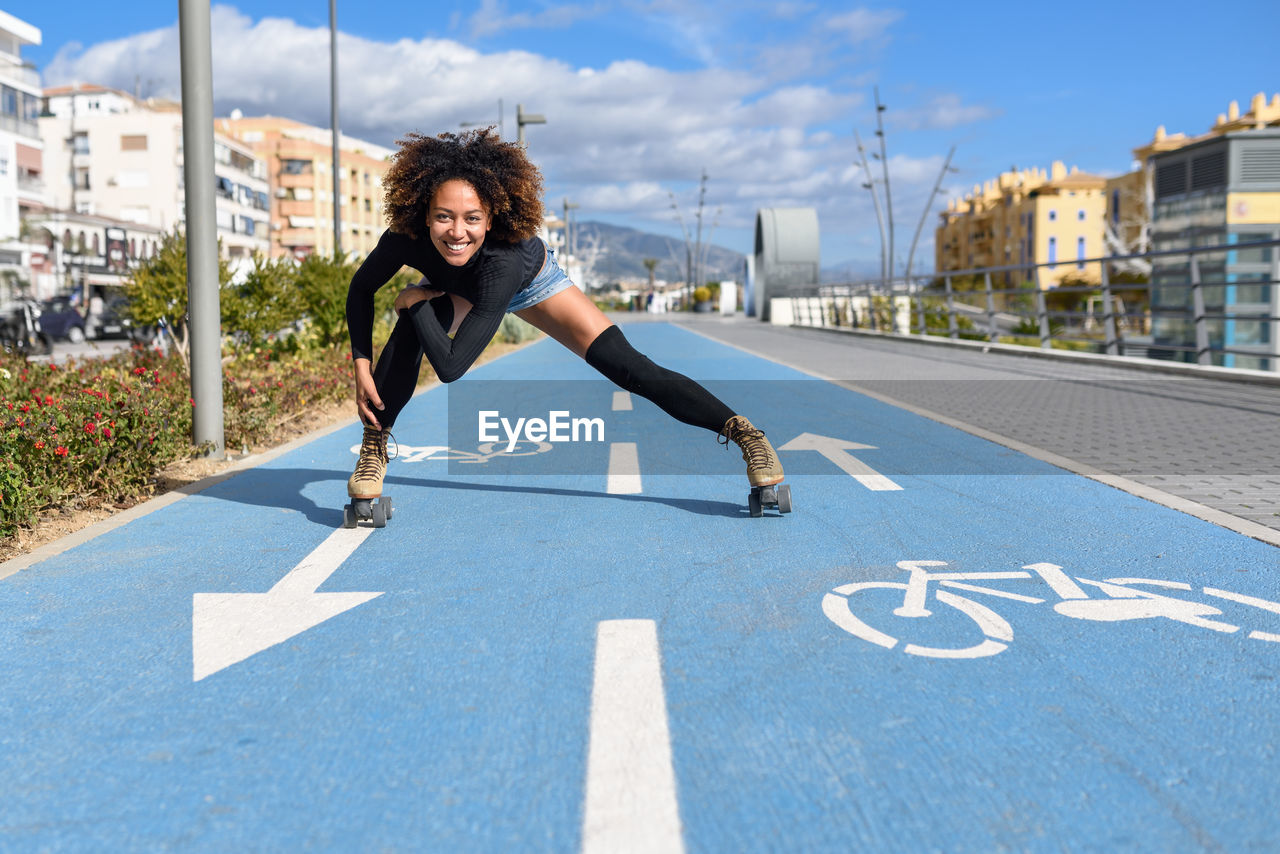 Portrait of woman roller skating on bicycle lane in city