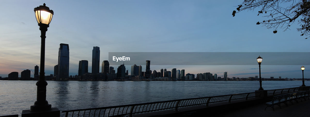 Sunset over hudson river with view between street lamps from manhattan shore to jersey city