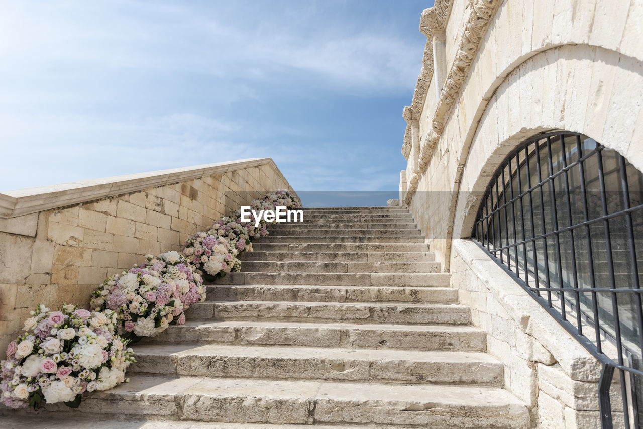 Low angle view of steps amidst buildings against sky