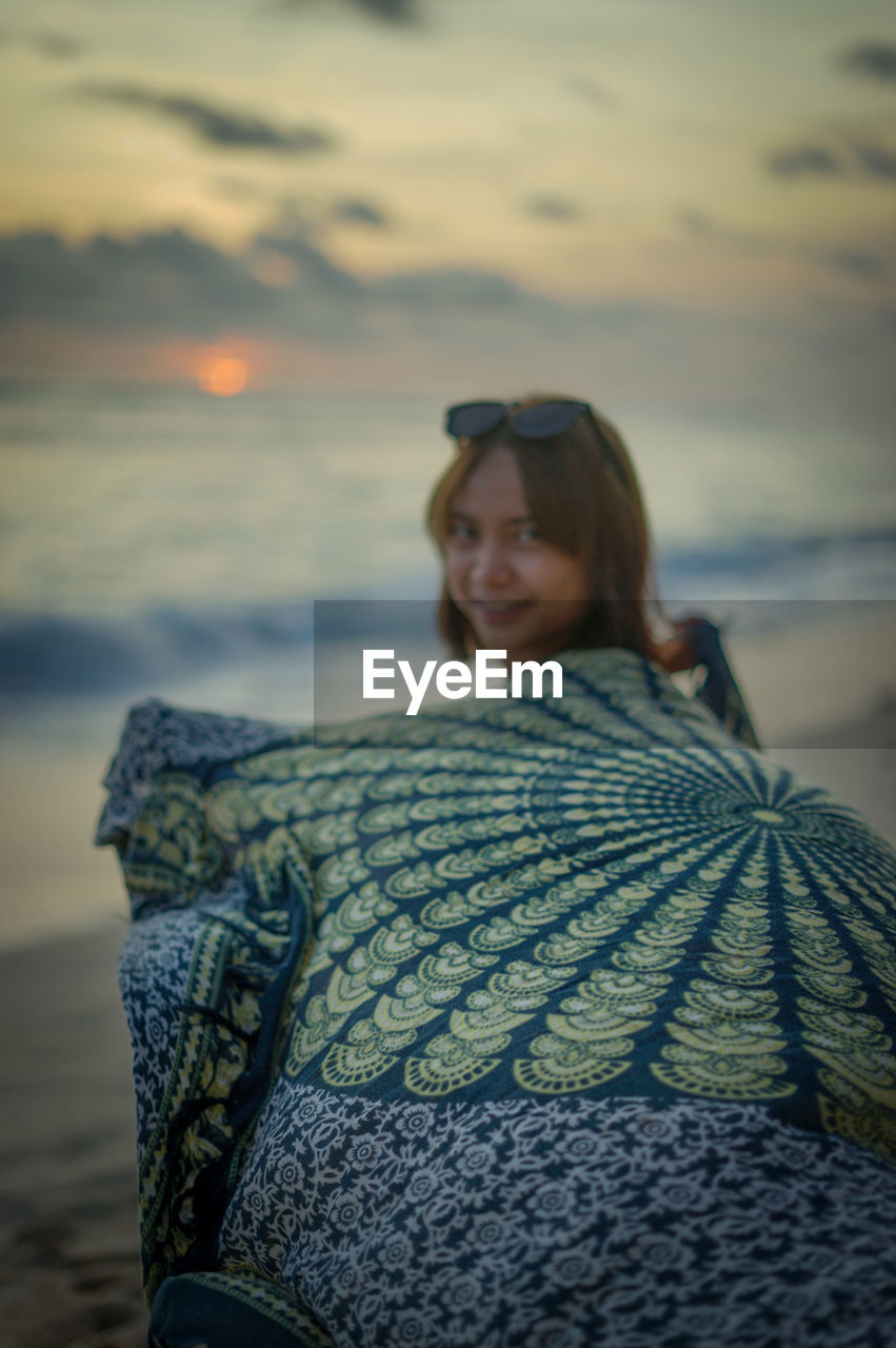 Portrait of smiling woman on beach during sunset