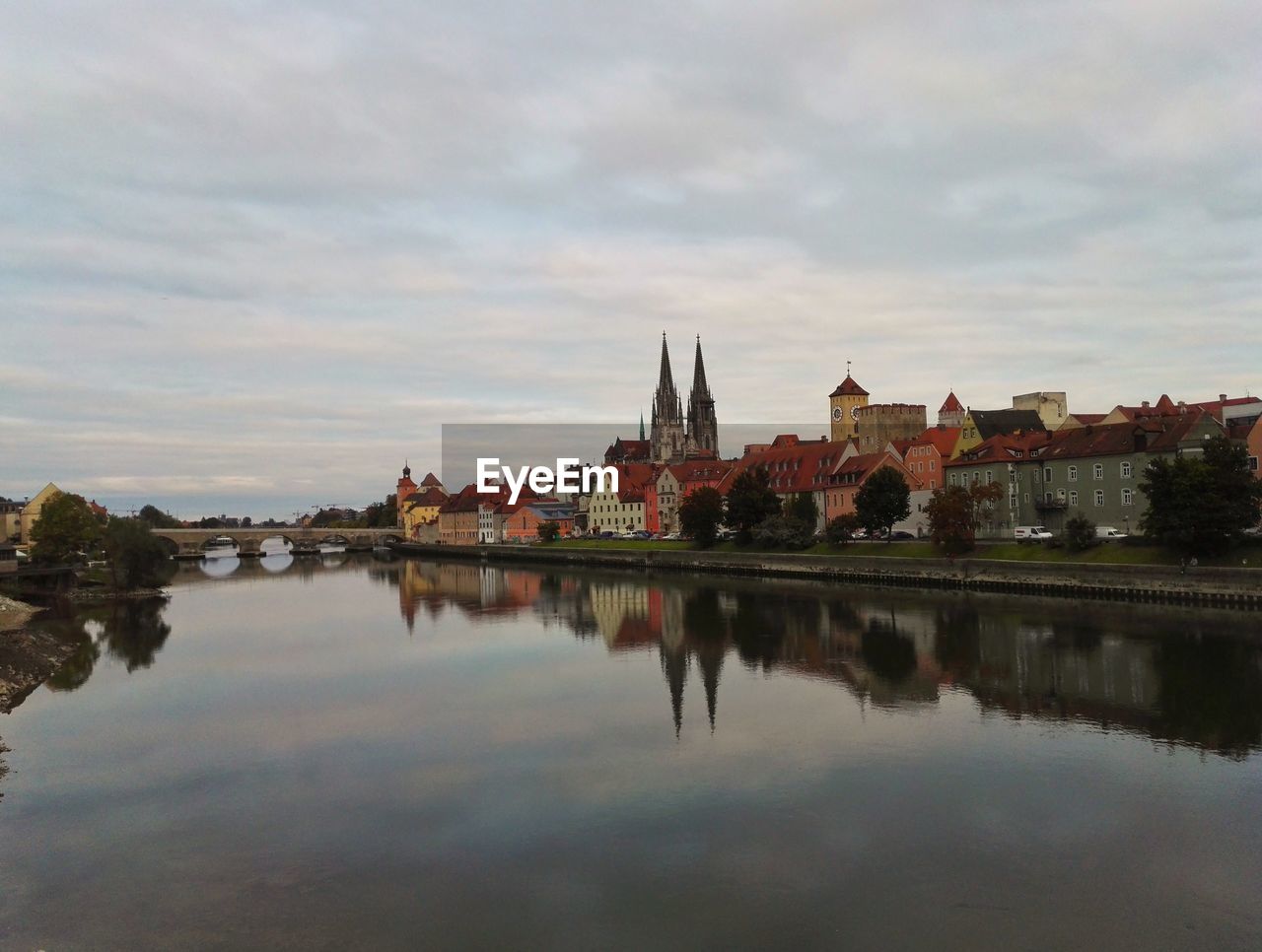 Reflection of buildings in lake against cloudy sky