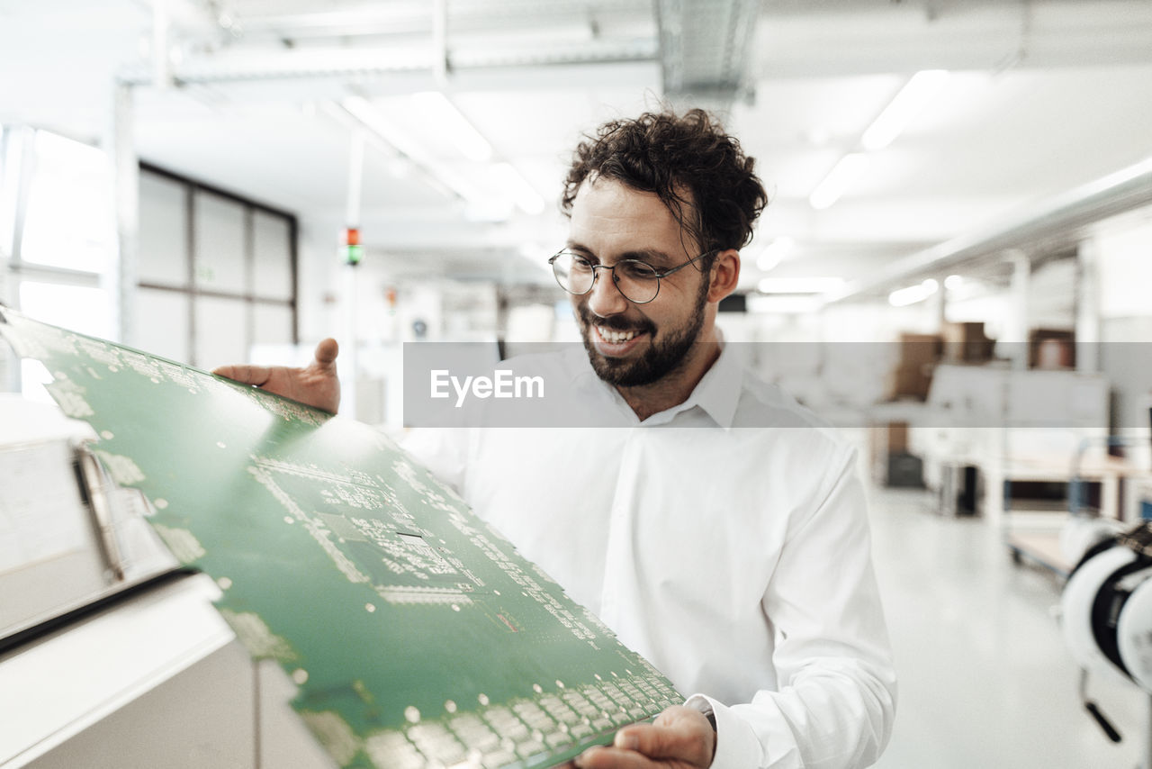 Smiling male technician analyzing large computer chip in industry
