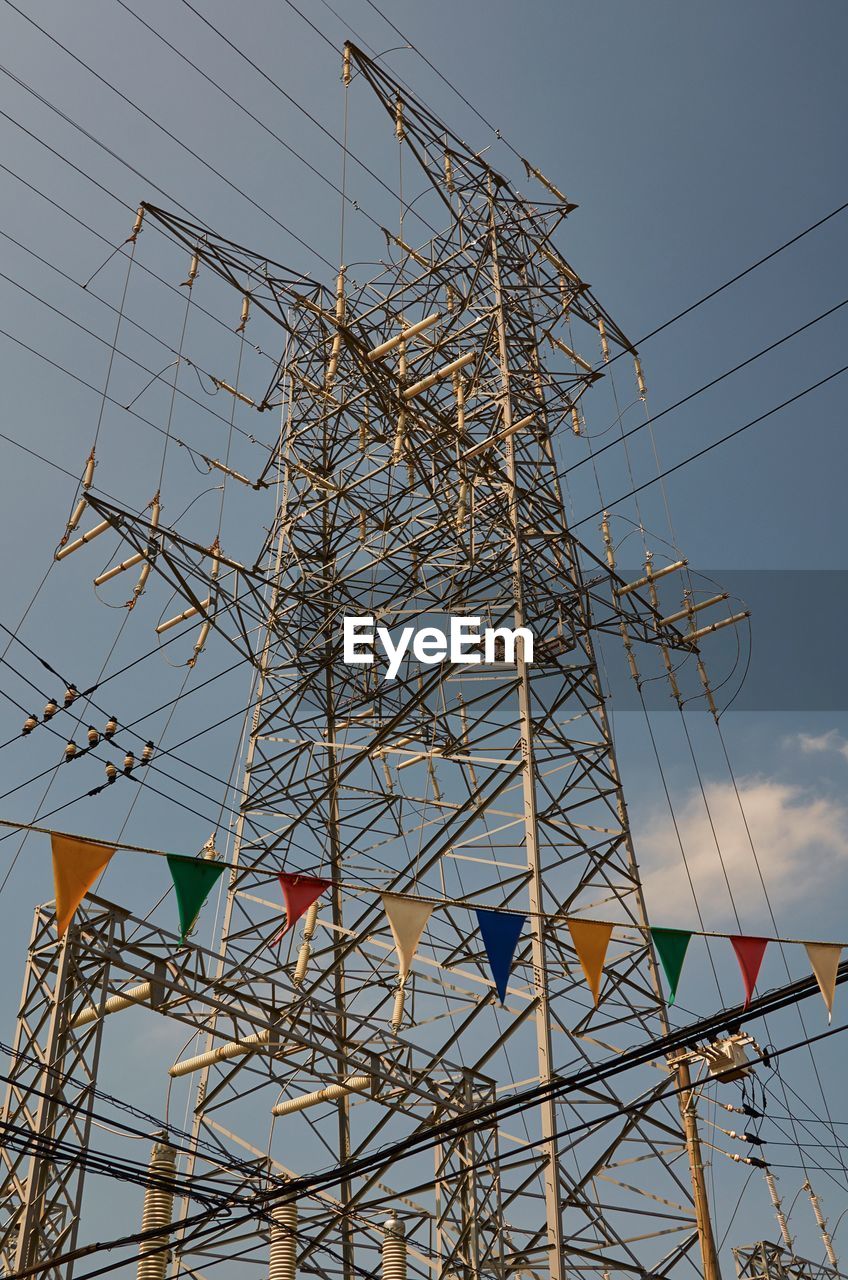 Low angle view of colorful bunting by electricity pylon
