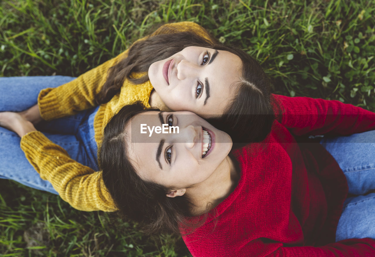 Smiling twin sister sitting on grass