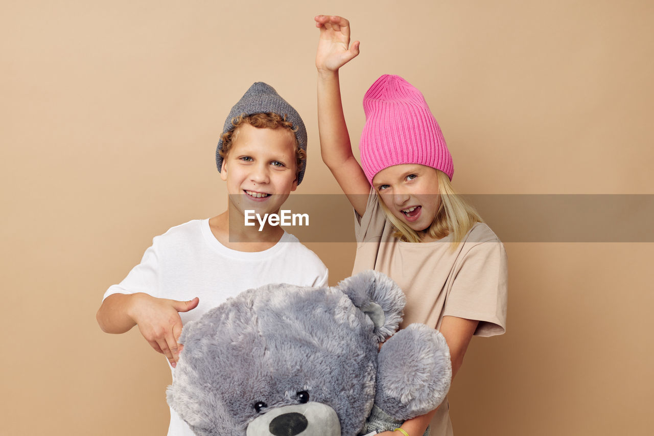 Portrait of smiling sibling against beige background