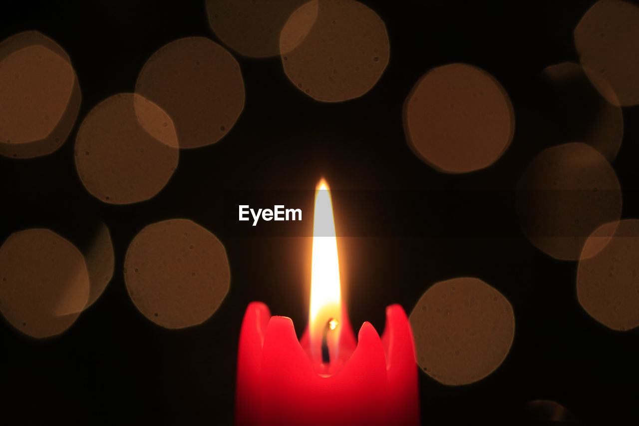 CLOSE-UP OF BURNING CANDLES IN DARKROOM