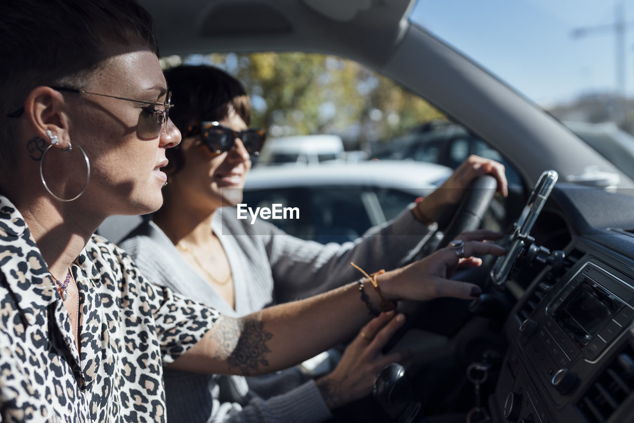 Woman using mobile phone while sitting with friend driving car