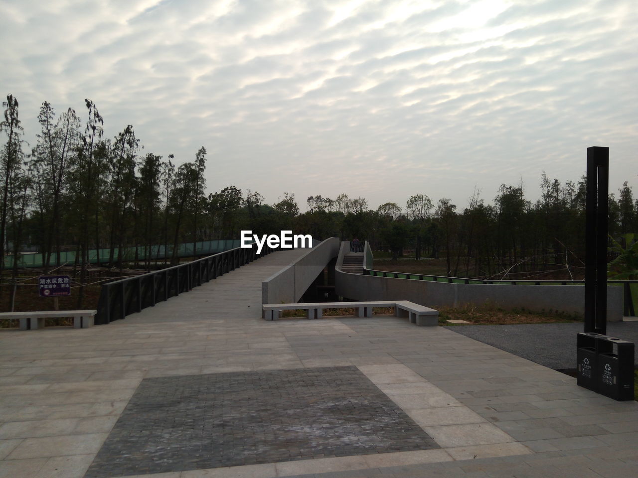 WALKWAY BY TREES AGAINST SKY