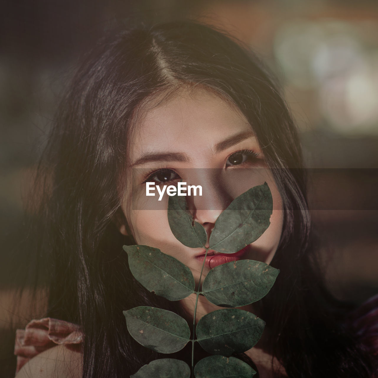 Close-up portrait of young woman with leaves