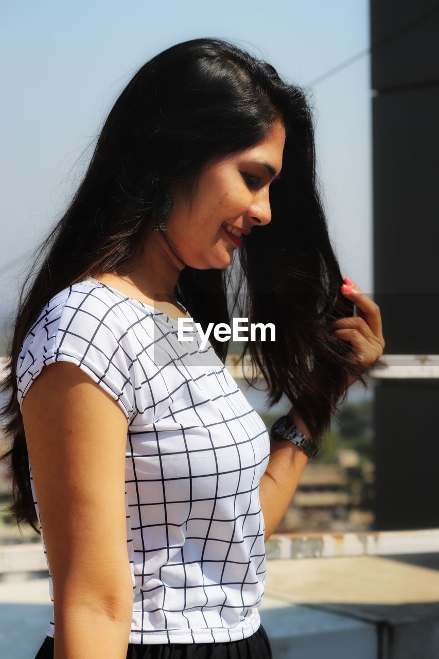 BEAUTIFUL YOUNG WOMAN LOOKING AWAY WHILE STANDING IN HAIR