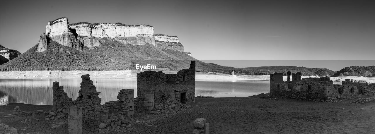 black and white, sky, architecture, monochrome, monochrome photography, land, nature, water, beach, history, built structure, travel destinations, ruins, ancient history, rock, the past, sea, scenics - nature, travel, no people, mountain, landscape, white, building exterior, building, panoramic, outdoors, environment, tourism, day, old ruin, black, clear sky, castle, tranquility