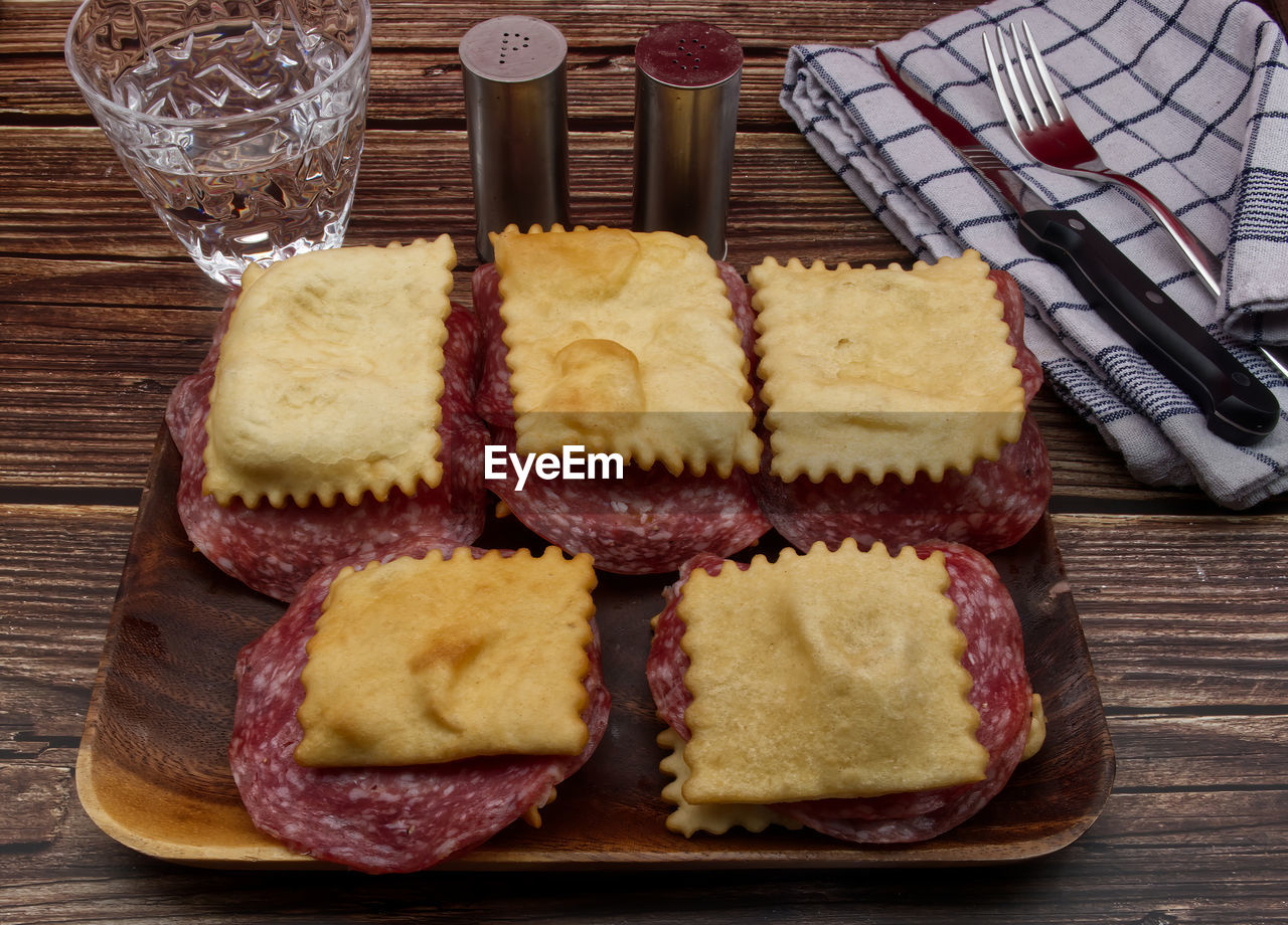 Italian gnocco fritto food with salami on rustic wooden table. 
