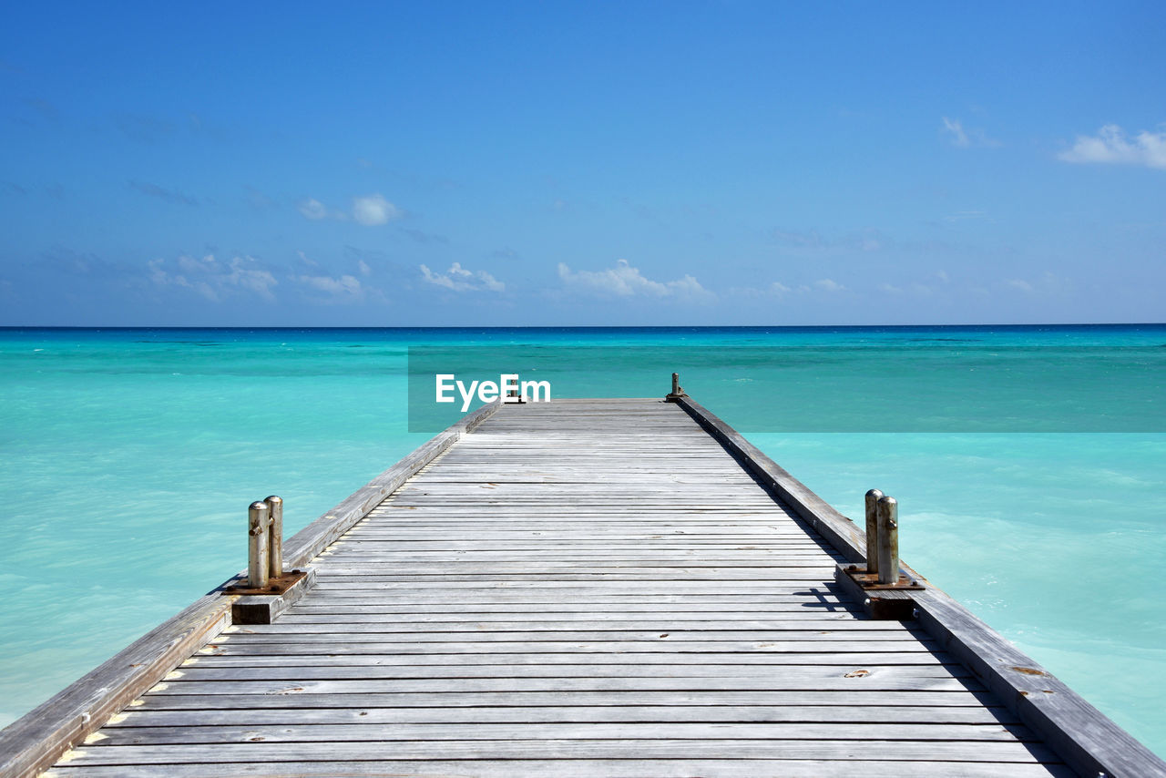 Pier over sea against blue sky