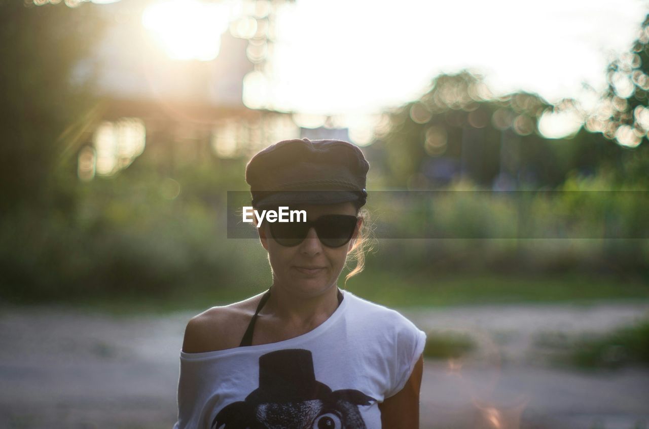 Woman in sunglasses and cap standing outdoors