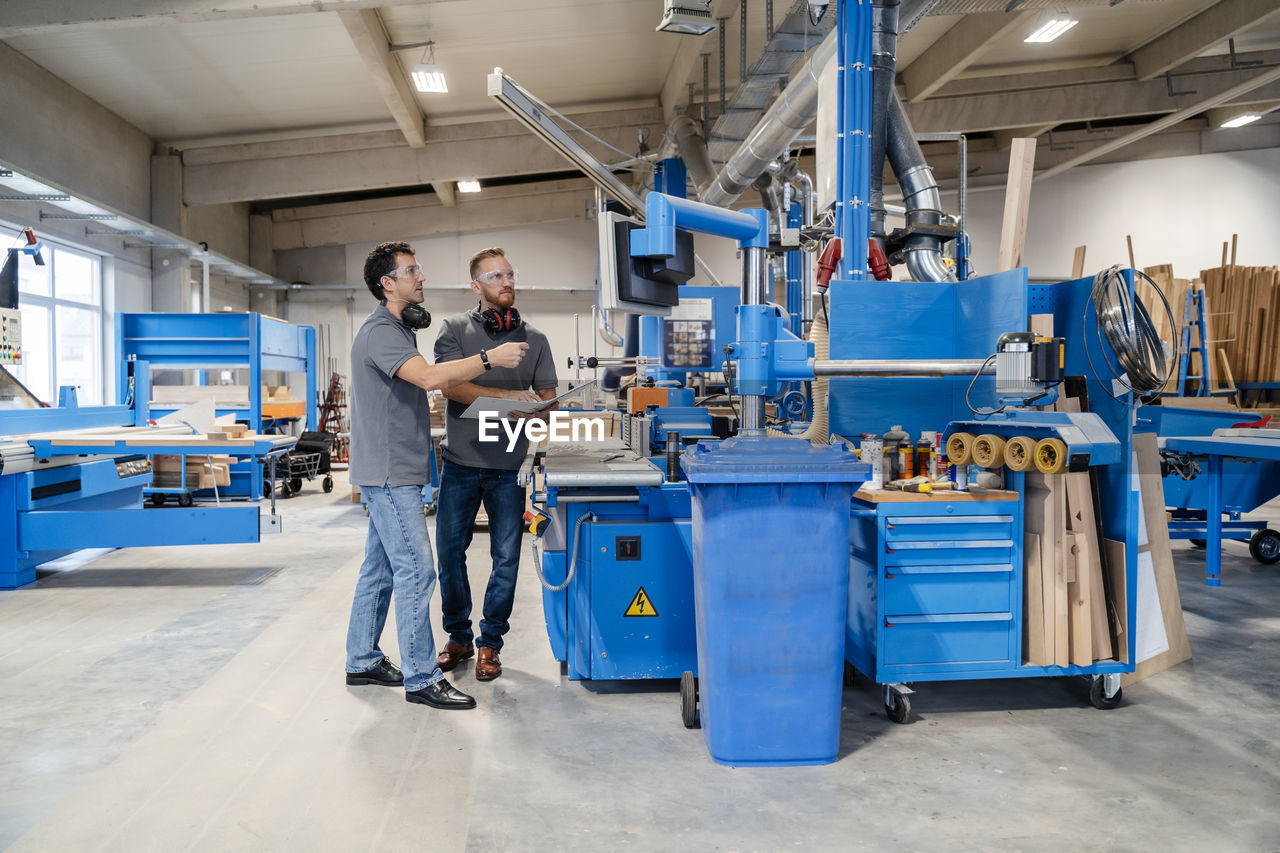 Two male carpenters talking in production hall