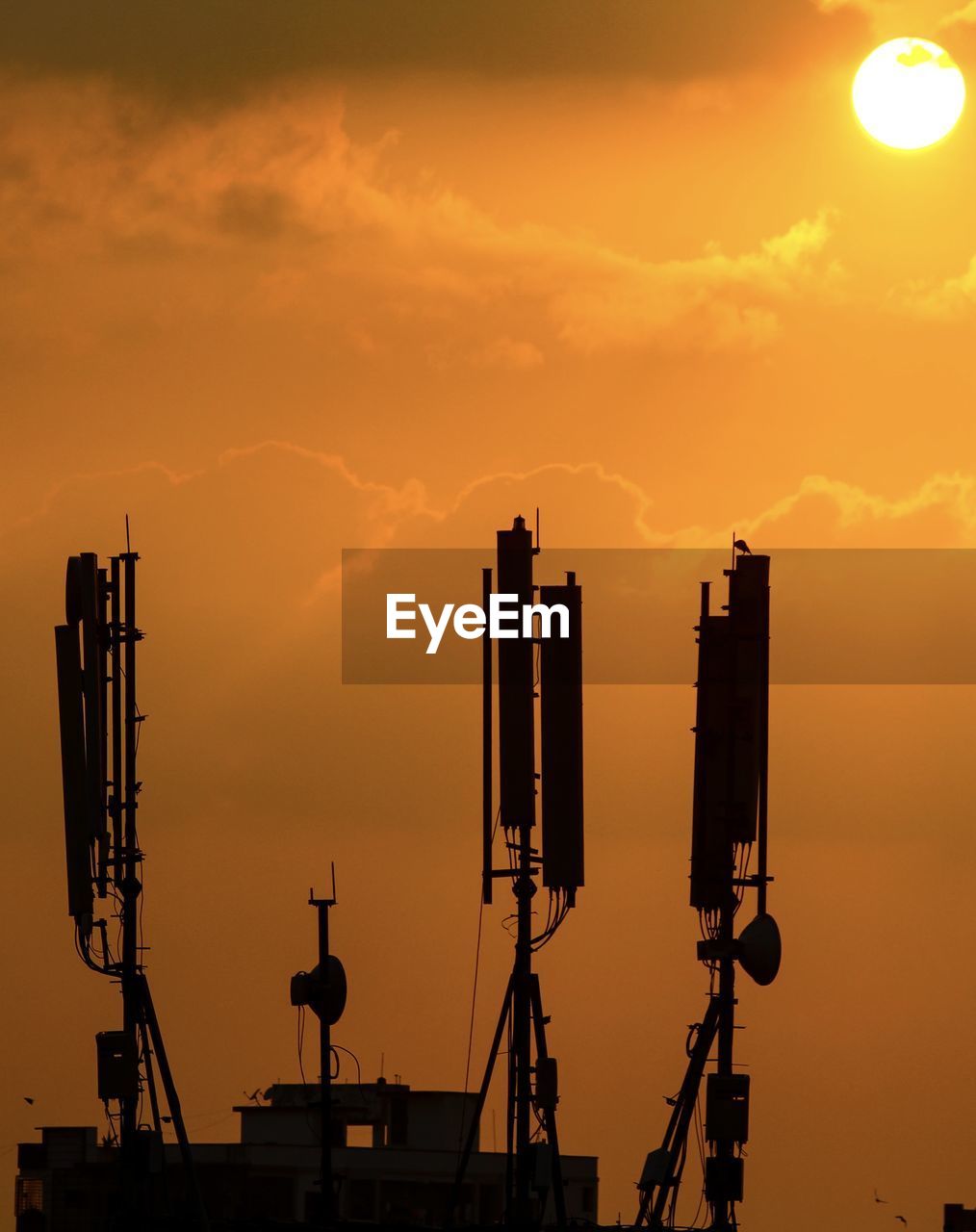 Low angle view of silhouette dishes against orange sky