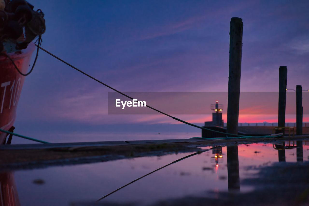 Reflection of wooden post in lake at sunset